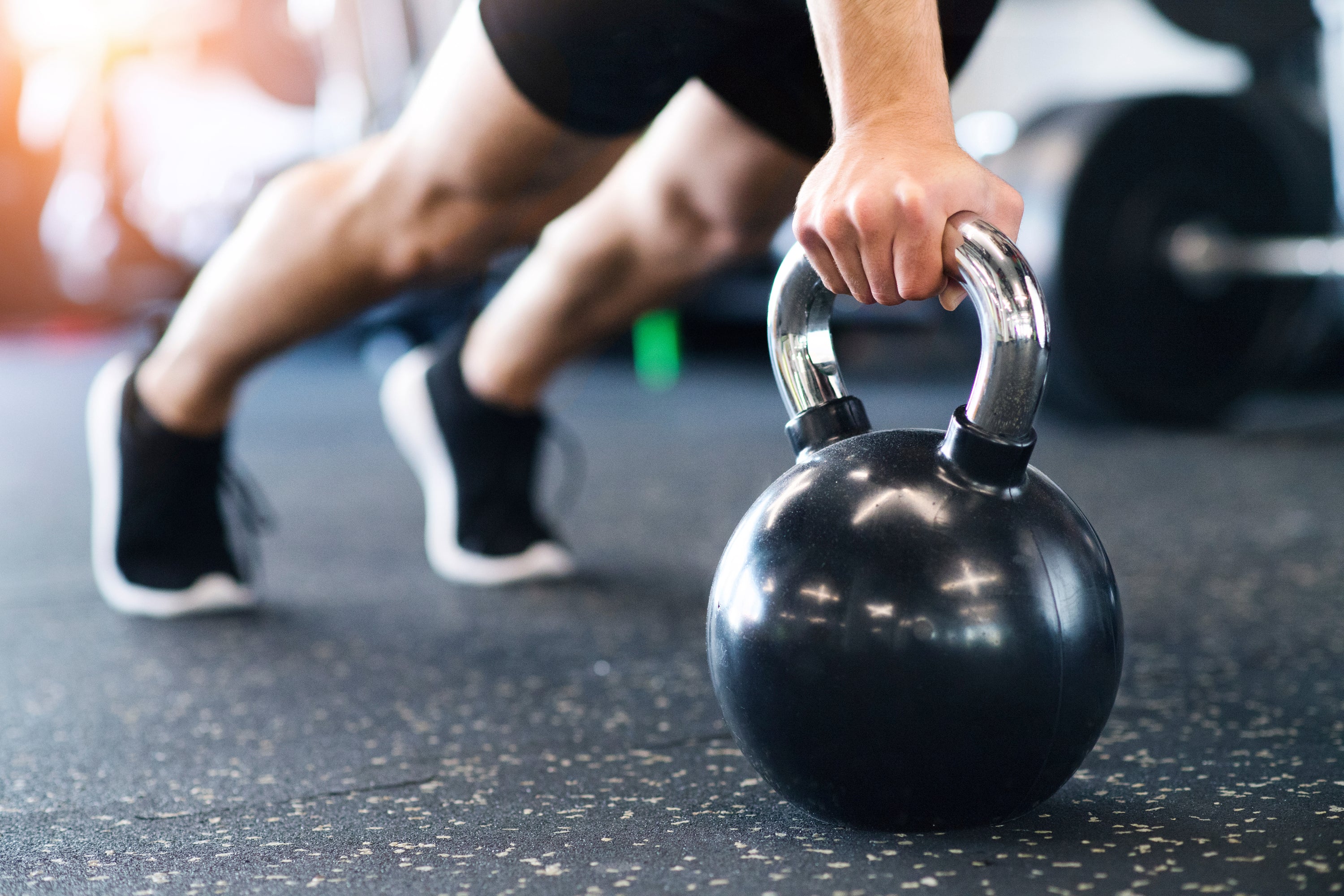 Man doing a pushup using a black kettlebell on rubber gym flooring