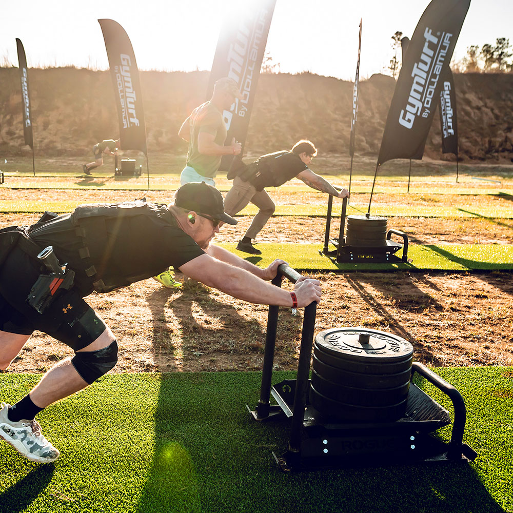 Tactical Games athletes pushing weighted sleds on GymTurf